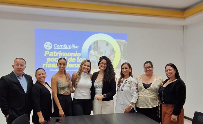 Ocho personas en traje de negocios posan y sonríen ante una diapositiva en la que se lee "Comfamiliar Patrimonio social de los risaraldenses", que representa el compromiso de Comfamiliar Risaralda con el fortalecimiento del sector y el turismo en la mesa de conferencias.