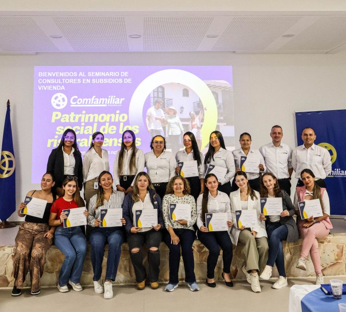 Un grupo de personas, en su mayoría mujeres, posan en un escenario sosteniendo certificados, celebrando que han terminado un seminario de consultores. Detrás de ellos, una gran pantalla muestra el logotipo de Comfamiliar y el texto Patrimonio social de los risaraldenses. Todos sonríen.