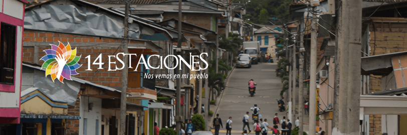 Una escena callejera en La Celia, Risaralda, con casas coloridas, gente caminando y niños cruzando la calle. Texto superpuesto que dice 14 Estaciones - Nos vemos en mi pueblo con un vibrante logo de flores.