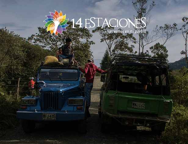 Dos coloridos jeeps están aparcados en una carretera rural de Mistrató, en Risaralda, con gente cargando objetos en el azul. Árboles y montañas forman el telón de fondo. El logotipo de 14 Estaciones y un texto en español aparecen en la parte superior de la imagen.