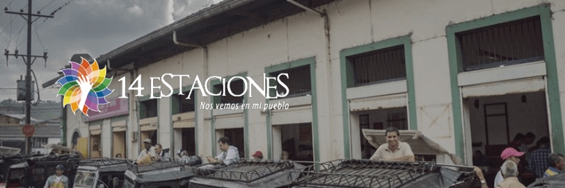 La gente se reúne frente a una hilera de edificios antiguos con portales arqueados en Risaralda. El logo de 14 Estaciones y la frase Nos vemos en mi pueblo aparecen sobre la imagen. Varios vehículos estacionados frente a las Estaciones Santa Rosa de Cabal.
