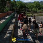 Un grupo de jóvenes con faldas de hierba practican un baile en una cancha de baloncesto al aire libre rodeada de montañas y vegetación en Mistrató. En la parte inferior se ve el logotipo de Comfamiliar Mistrató, que destaca las actividades comunitarias cerca de la Biblioteca Pública.