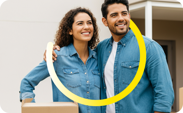 Una pareja sonriente con camisas vaqueras está de pie, muy juntos, sujetando cajas de mudanza en el exterior de un edificio. Un gráfico curvo amarillo cubre parte de la imagen.