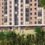 Un moderno edificio de apartamentos de varias plantas con balcones y grandes ventanales, rodeado de vegetación; la gente pasea y se sienta en los bancos de la zona ajardinada exterior.