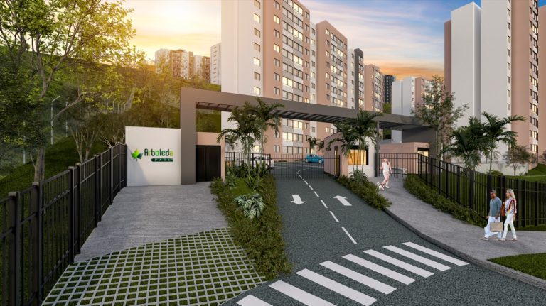 Una entrada a un moderno complejo residencial cerrado con altos edificios de apartamentos, una verja de seguridad, un cartel que dice Robledal cerca del Parque Arboleda, zonas verdes ajardinadas y gente caminando por la acera al atardecer.
