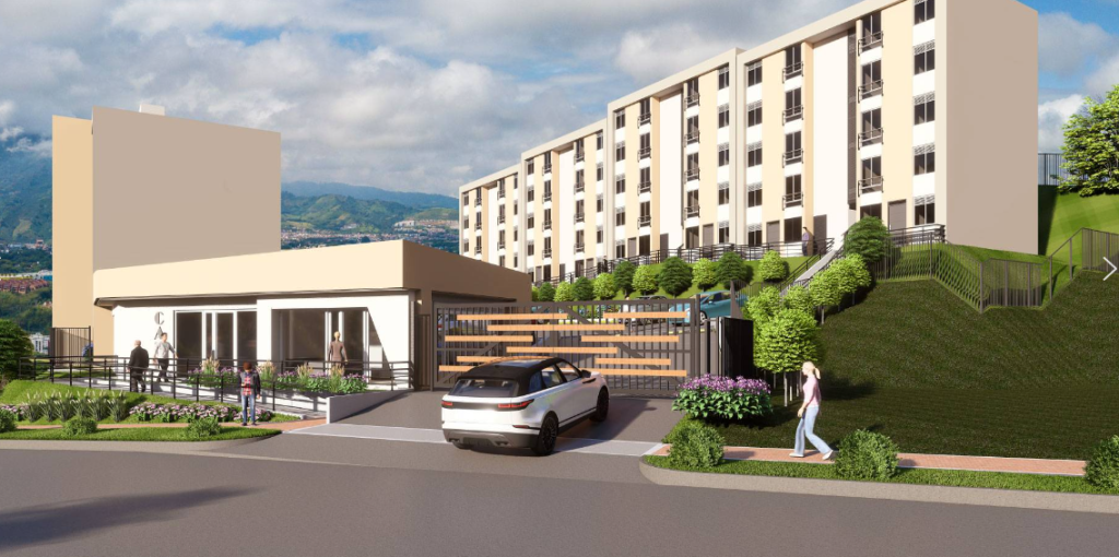 Un coche blanco entra en un complejo residencial cerrado con un edificio de apartamentos de varios pisos de color beige, una entrada moderna y zonas verdes ajardinadas. La gente camina por la acera y cerca de la entrada. El cielo está parcialmente nublado.