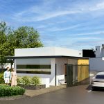 Una moderna garita de seguridad con grandes ventanales se encuentra junto a la entrada del Portal de la Estación. Un coche blanco espera en la puerta, mientras dos personas permanecen de pie cerca. Árboles y arbustos verdes rodean la zona bajo un cielo azul parcialmente nublado.