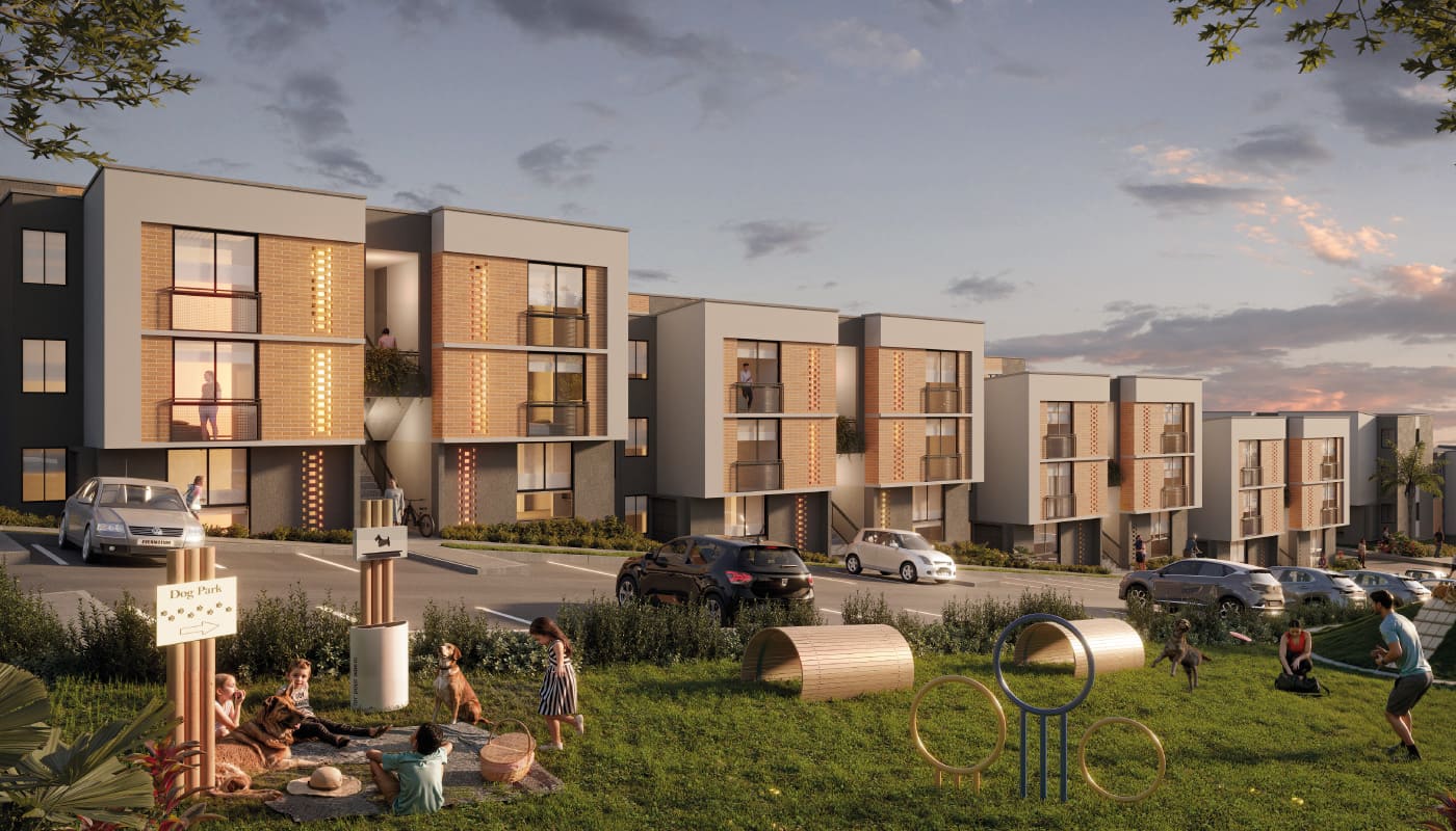 Los modernos edificios de apartamentos de Villabosque Nativo, con grandes ventanales y balcones al atardecer, dan a zonas de juego cubiertas de hierba, donde los niños ríen y les espera un parque para perros con túneles y aros. Varios coches aparcan delante de las elegantes residencias.