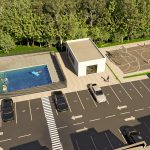 Vista aérea de la zona exterior del Portal de la Estación con piscina, tumbonas, un pequeño edificio, cancha de baloncesto y plazas de aparcamiento adyacentes, todo ello rodeado de árboles.
