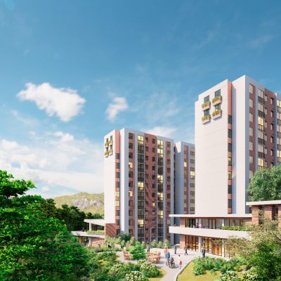 Modernos edificios de apartamentos con fachadas rojas y blancas se elevan sobre zonas verdes ajardinadas, árboles y senderos bajo un cielo azul brillante con nubes dispersas. La gente pasea y se reúne alrededor de los edificios.