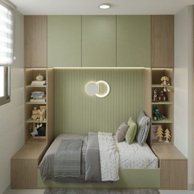 Un dormitorio moderno y compacto en Torres del Bosque con una cama individual rodeada de estanterías de madera empotradas y armarios verdes, con una iluminación suave, juguetes, libros y una lámpara de pared redonda sobre la cama. Una gran ventana a la izquierda deja entrar la luz natural.