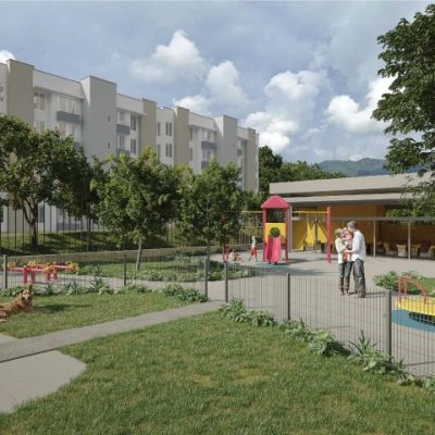 Un moderno parque infantil al aire libre con equipos de colores está rodeado de hierba verde, árboles y una valla baja. Familias con niños y un perro disfrutan de la zona, con los edificios de apartamentos Torres del Bosque visibles al fondo.
