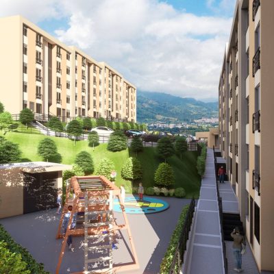 Un moderno complejo de apartamentos con edificios de color beige, zonas verdes ajardinadas, un parque infantil con columpios y bancos reservados se asienta a lo largo de un camino por el que la gente pasea en un día soleado, con las majestuosas montañas de las Serranías al fondo.