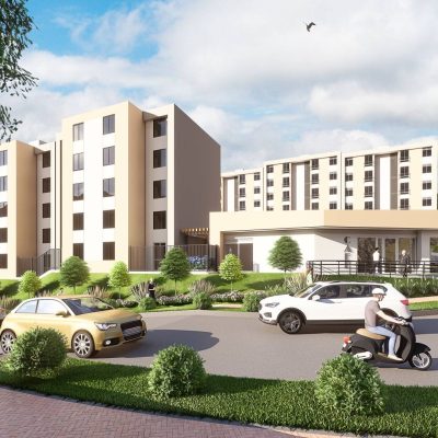 Un moderno complejo residencial, Serranías Reservado, presenta varios edificios de mediana altura de color beige, coches y una scooter en una carretera de curvas, todo ello rodeado de un exuberante paisaje verde bajo un cielo parcialmente nublado.