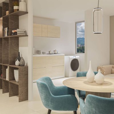 Moderno salón diáfano con mesa de comedor, sillas de color verde azulado, sofá beige, estanterías empotradas, zona de despacho reservada con ordenador y cocina compacta con lavadora junto a la ventana, perfecta para disfrutar de las vistas de las Serranías.