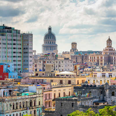 Paisaje urbano de La Habana, Cuba, con coloridos edificios, arquitectura antigua y la prominente cúpula de El Capitolio bajo un cielo parcialmente nublado, todo ello capturado desde una perspectiva de plano bajo.