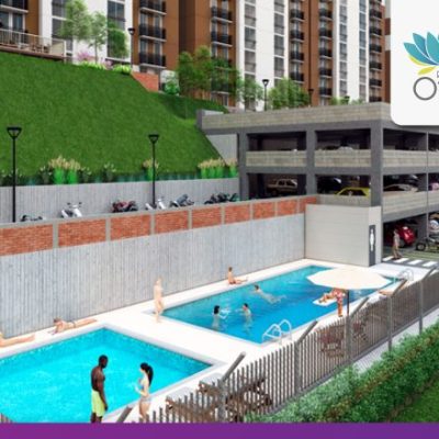 Piscinas al aire libre con gente nadando y relajándose, junto a una estructura de aparcamiento de varios niveles y una ladera cubierta de hierba. Al fondo se ven altos edificios de apartamentos, incluidos los de Riveras del Otún. El logotipo de la Reserva del Otún aparece en la esquina superior derecha.