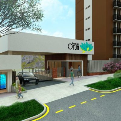 Entrada principal del complejo de apartamentos Riveras del Otún con una moderna verja, gente paseando, un coche aparcado, zonas verdes ajardinadas y un edificio alto al fondo. Un coche blanco en la calle de enfrente.