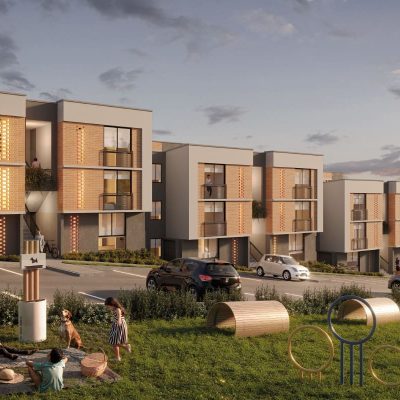 Los modernos edificios de apartamentos de Villabosque Nativo, con grandes ventanales y balcones al atardecer, dan a zonas de juego cubiertas de hierba, donde los niños ríen y les espera un parque para perros con túneles y aros. Varios coches aparcan delante de las elegantes residencias.