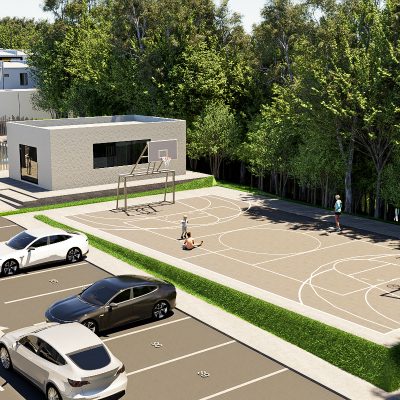 Una moderna cancha de baloncesto al aire libre cerca del Portal de la Estación se encuentra junto a un aparcamiento con varios coches. Unas pocas personas juegan en la cancha, mientras un pequeño edificio rectangular con una zona vallada descansa cerca, todo rodeado de densos árboles.